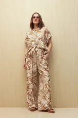 Pantalón ancho de tela liviana con estampado de hojas color crema sobre fondo azul. Tiene cintura elastizada con lazo ajustable.