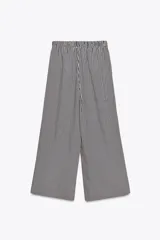 Pantalón de tiro medio con cintura elástica y bolsillos laterales ocultos en costura. Pierna ancha y diseño a rayas verticales azules y blancas.