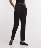 Pantalón de vestir negro de corte carrot, con cintura alta, trabillas y cinturón con hebilla metálica.