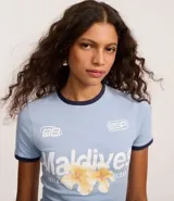 Remera ajustada de algodón color celeste claro con cuello redondo y ribetes en azul marino. Presenta un estampado frontal con la palabra "Maldivas" en blanco y un diseño floral en tonos amarillos y naranjas. Incluye pequeños logos bordados en blanco en el pecho.
