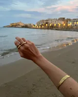 Brazalete rígido dorado con textura irregular.