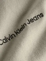 Sweater de punto fino color beige, con cuello redondo y logo "Calvin Klein Jeans" bordado en el pecho.