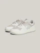 Zapatillas urbanas Tommy Jeans de corte bajo, con exterior de piel en tonos blanco, gris y beige. Presentan suela gruesa de goma, cordones y logo de la marca en el lateral y el talón.