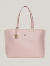Bolso tipo tote color rosa pálido, con doble asa de hombro y cierre superior con cremallera. Incluye un dije colgante con el logo de la marca y el logo metálico en la parte frontal.