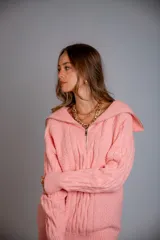 Buzo de punto color rosado, con cuello polo y cierre frontal parcial, de manga larga y diseño holgado.