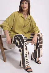 Camisa color verde oliva, de corte recto, con cuello camisero y mangas largas con puños abotonados.