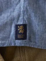 Camisa celeste a cuadros blancos, de manga larga y corte recto.