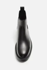 Bota Chelsea marrón de cuero, con elásticos laterales y tirador trasero. Suela negra con ligero tacón.