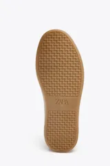 Zapatillas deportivas de mujer con combinación de materiales en negro, blanco y marrón. Cierre con cordones y suela en contraste color caramelo.