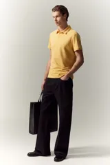 Remera polo de manga corta color amarillo, confeccionada en punto de algodón liviano. Tiene cuello clásico, tapeta con botones y corte ajustado.