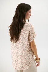 Blusa estampada con hojas azules sobre fondo blanco, con cuello en V y mangas cortas con dobladillo.