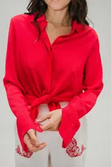 Camisa roja de crepé fluida con cuello camisero, mangas largas con puños abotonados y cierre frontal con botones.