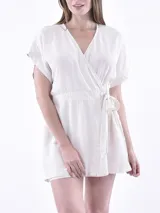Vestido corto color crudo, con escote cruzado, mangas cortas y lazo en la cintura.