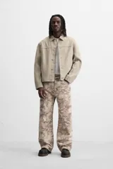 Pantalón de jean de corte recto con estampado abstracto en tonos beige, marrón y gris.