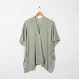 Ruana color verde claro de tejido de punto con cuello en V y cierre con un botón.