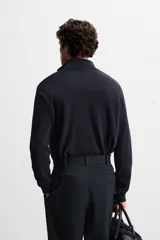 Jersey negro de punto de algodón, corte recto, cuello perkins con cremallera metálica y mangas largas terminadas en rib.