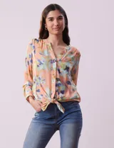 Blusa de gasa estampada con cuello a la base, escote en V y botones. Tiene un bolsillo aplicado en el frente. Las mangas largas son regulables con presilla y botón. La terminación es anudada opcional.