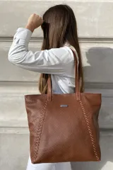 Bolso grande tipo tote de cuero color marrón con costuras decorativas en los laterales, forro interior con bolsillo para celular y bolsillo con cierre. Incluye bolsillo trasero con cierre y correas largas para colgar del hombro.