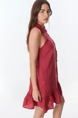 Vestido corto color ladrillo, sin mangas, con cuello camisero con volados, abotonado al frente y falda con volados.