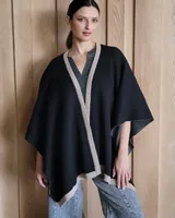 Ruana negra de tejido de punto con una estrella grande color beige en la espalda y borde inferior con franja beige.