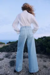 Pantalón de jean celeste de pierna ancha, tiro alto, con bolsillos de parche delanteros y traseros.