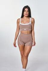 Conjunto deportivo color marrón con detalles en blanco, compuesto por un top con breteles finos y un short ajustado.