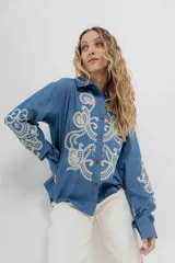 Camisa de denim azul con bordados en color crudo, de corte relaxed, manga larga y botones frontales.