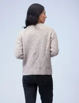 Buzo de tejido melange color beige con puntos oscuros, cuello redondo y manga larga.