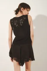 Top negro sin mangas confeccionado en mesh con bordado de flores a tono.
