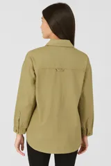 Sobrecamisa azul de jean con corte holgado, cuello camisero, cierre con botones a presión y dos bolsillos de parche en el pecho.
