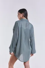 Camisa celeste con bordado de hojas blancas en el frente, de corte clásico y mangas largas.