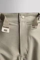 Pantalón de hombre color beige/caqui, de corte regular fit, confeccionado en tejido técnico compacto con elasticidad. Presenta cintura ajustable con cinturón a contraste, bolsillos frontales, bolsillo trasero con cierre de cremallera oculta y bolsillo cargo con cierre de cremallera oculta en la pernera.