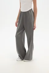 Pantalón deportivo negro de corte ancho y tiro alto, con cintura elástica y cordón ajustable. Presenta una raya blanca vertical a cada lado.