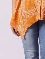 Camisa naranja con estampado cachemir, cuello mao, escote en V y cierre frontal con botones. Mangas 3/4 regulables con presilla y ruedo asimétrico.