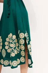 Vestido tipo túnica largo midi de viscosa color verde esmeralda con bordados florales en color crema. Tiene mangas al codo y lazo de ajuste en la cintura.