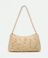 Cartera de mano color beige, tejida en rafia, con cadena dorada y apliques de dijes con forma de estrellas de mar, caracoles y perlas.