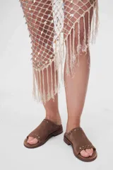 Sandalias bajas de cuero color marrón con detalles de tachas metálicas.