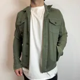 Chaqueta de jean verde militar con cuello clásico, cierre frontal con botones, cuatro bolsillos frontales con solapa y puños abotonados.