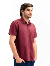 Camisa de manga corta color bordó confeccionada en algodón. Tiene corte clásico, cuello camisero, cierre con botones y bolsillo en el pecho.