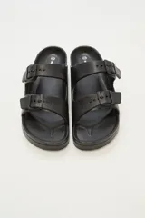 Sandalias planas color beige con doble tira y hebillas ajustables.