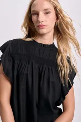 Blusa negra sin mangas con cuello redondo y detalle de volados en los hombros.