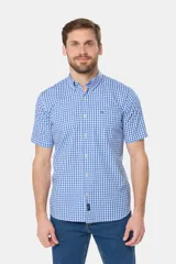 Camisa de manga corta con estampado a cuadros azules y blancos, bolsillo en el pecho con logo bordado y botones personalizados. Hecha en Uruguay.