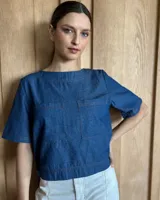 Remera negra con cuello redondo y mangas cortas, con detalle de pespuntes blancos en cuello, mangas, bolsillos frontales y ruedo.
