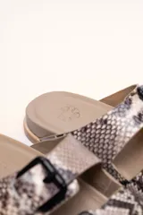 Sandalias marrones de cuero vacuno con doble tira y hebillas metálicas ajustables.