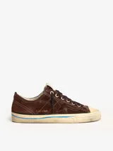 Zapatillas bajas marrones de gamuza con cordones negros, suela color crema con línea celeste y detalle de estrella calada en el lateral.