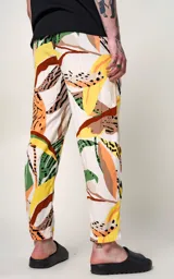 Pantalón recto unisex con estampado abstracto en tonos verde, naranja, amarillo y marrón sobre fondo blanco. Tiene bolsillos laterales y corte regular. Confeccionado con energías renovables en Argentina.