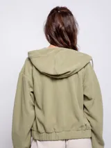 Campera cropped verde militar de polar con capucha y cuello alto, cierre frontal a tono, puños y cintura elastizados. Tiene dos bolsillos frontales de nylon con solapa.
