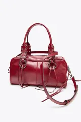 Bolso bowling color rojo con efecto craquelado. Tiene doble asa de hombro con detalles metálicos y asa bandolera extraíble. Incluye bolsillo interior con cremallera y cierre principal con cremallera.