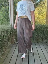 Pantalón de lino azul marino con rayas verticales blancas, corte palazzo, cintura alta con elástico y cinturón de raffia con hebilla redonda.