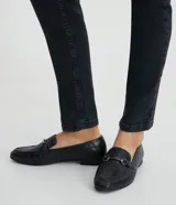 Mocasines negros con textura croco, puntera redondeada y detalle metálico en la parte superior.